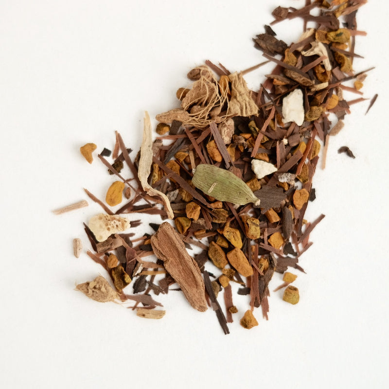 A close up of organic turmeric chai, called Witch Doctor. This tea is formulated by The New New Age and features pau d'arco, turmeric, sarsaparilla, ginger, burdock root, black peppercorns, star anise, cinnamon, cardamom, cat's claw, orange peel.