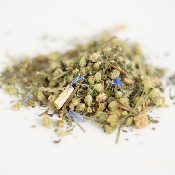 A close up of Wounded Healer. An organic herbal tea formulated by The New New Age, this tea features yarrow, ginger, lemon verbena, lemongrass, lemon balm, blue cornflower, black pepper.
